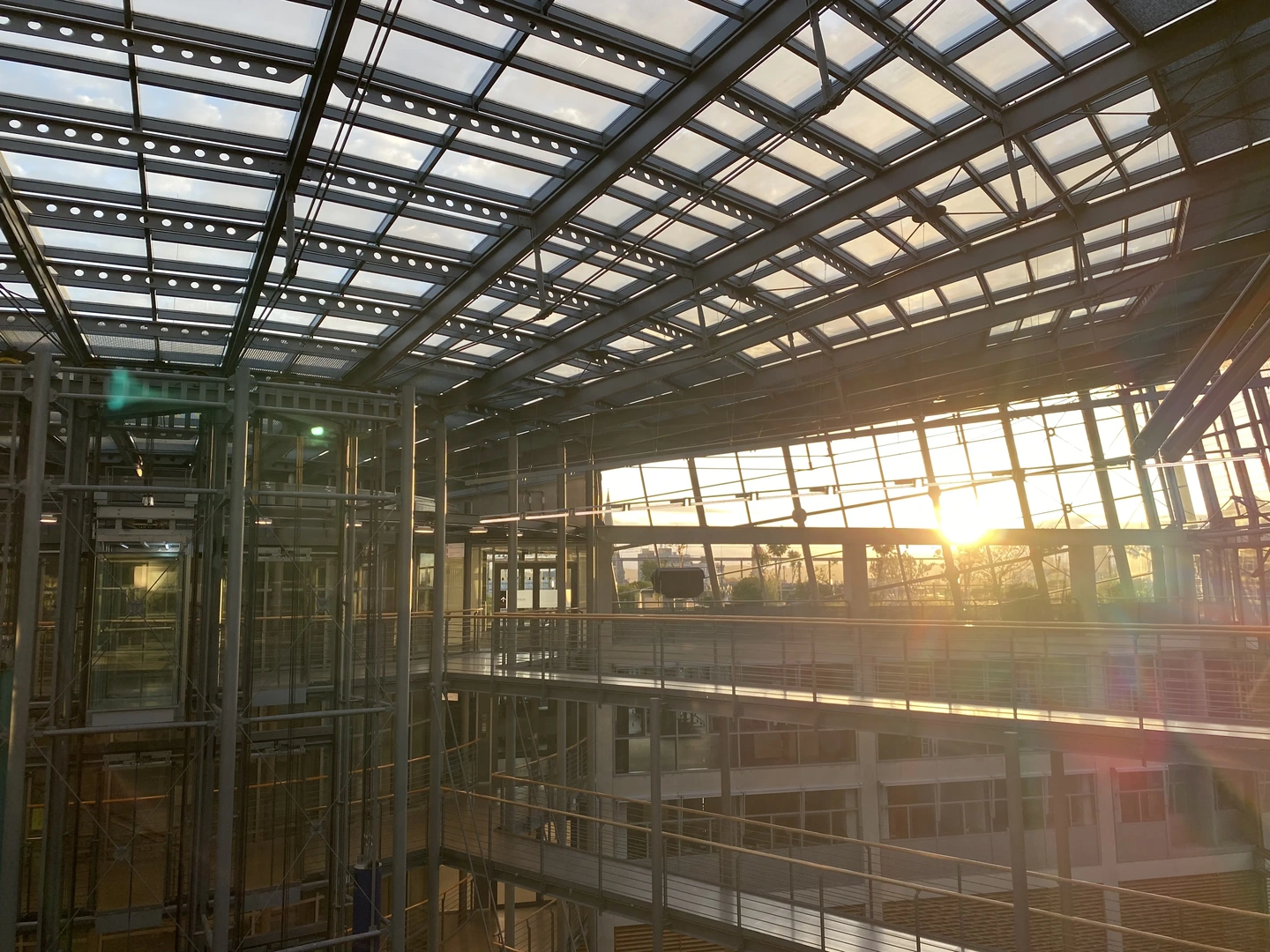 Eine Wissenschaftlerin und ein Wissenschaftler arbeiten hinter einer Glasfassade und mischen Chemikalien mit Großgeräten.