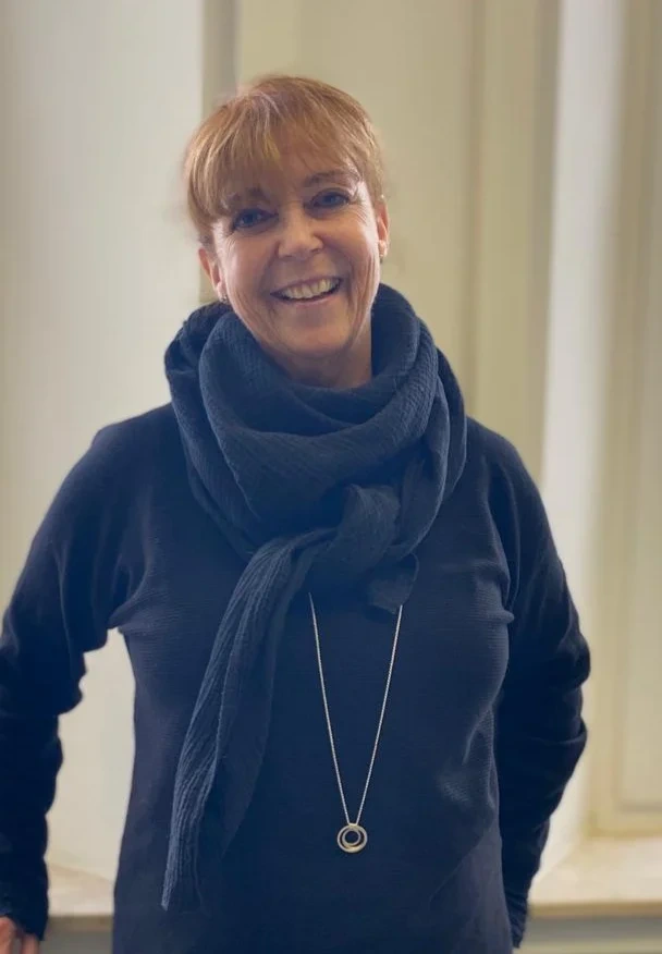 Eine Wissenschaftlerin und ein Wissenschaftler arbeiten hinter einer Glasfassade und mischen Chemikalien mit Großgeräten.