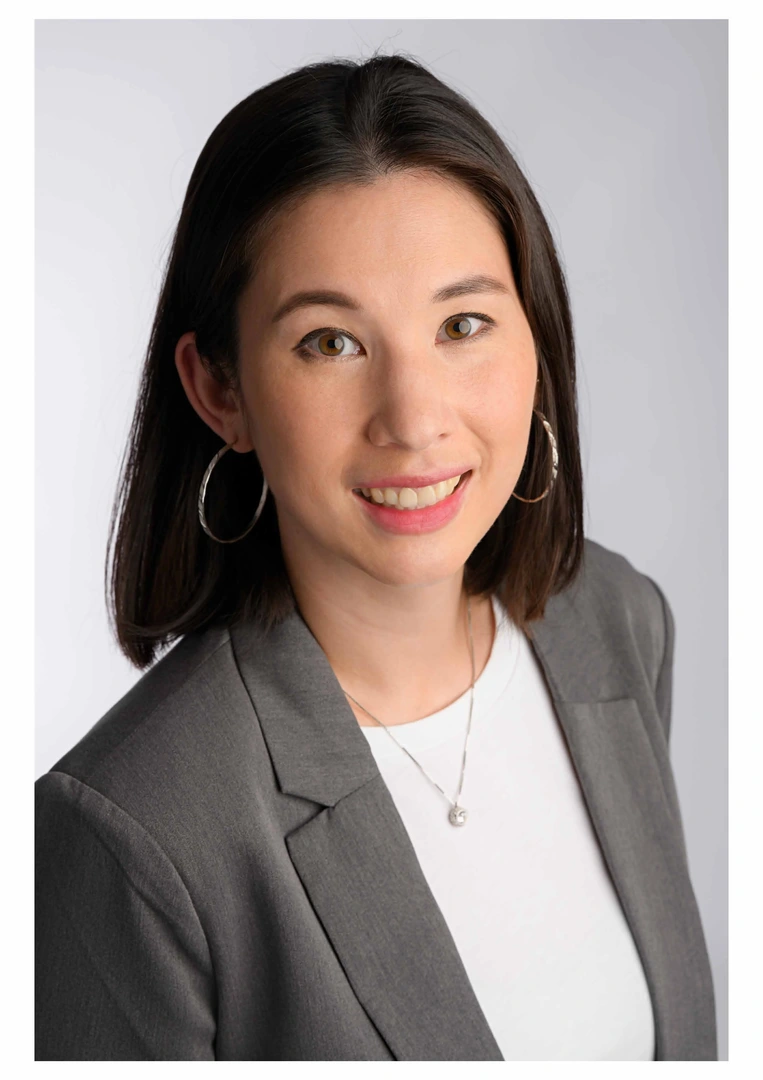 Eine Wissenschaftlerin und ein Wissenschaftler arbeiten hinter einer Glasfassade und mischen Chemikalien mit Großgeräten.